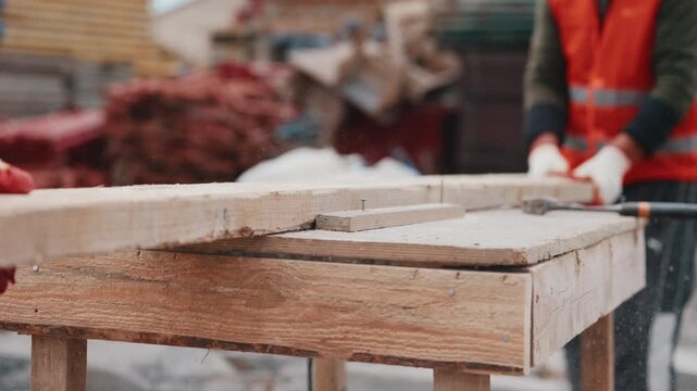 Cutting wooden formwork boards on workbench with circular saw close up