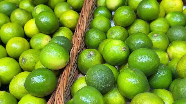 Limes baskets fresh, vibrant green limes heaped in woven basket. The textured skin and rich color emphasize their freshness and quality.