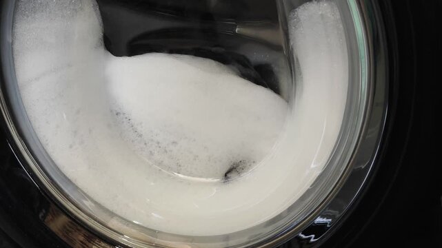 Washing machine drum full of soap foam and bubbles during wash cycle