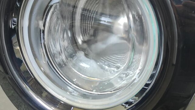 Empty washing machine drum rotating with water during a rinse cycle.