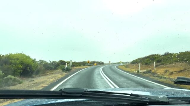 Driving car on a winding road with rain on windshield, great ocean road, victoria, australia.
