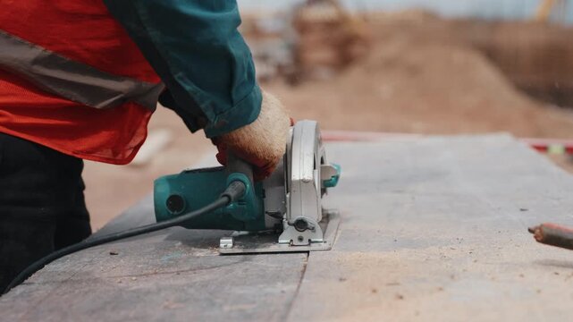 Cutting formwork panel with circular saw during construction close up