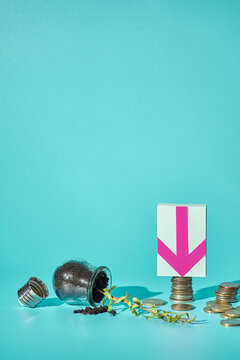 Vertical: fallen light bulb with euro coins, down arrow sticker on turquoise background, financial crash concept, copy space