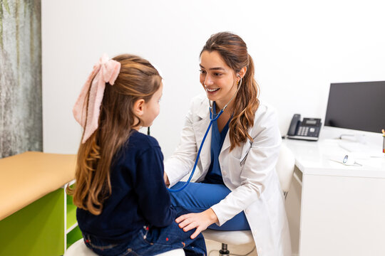 Heart rate check. Smiling female doctor using stethoscope to examine a young girl's heart and lungs, Healthcare and Medicine concept. Professional pediatrician consulting with child in clinic.