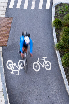 Urban cyclist with bicycle on bike lane road marking in Stockholm Sweden showing blur and motion during commute on city street in daylight
