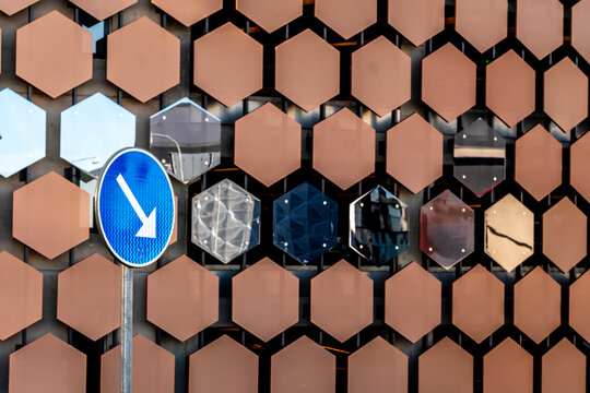 Urban facade pattern and geometry behind traffic sign with direction arrow guidance and instruction for drivers on street in daylight