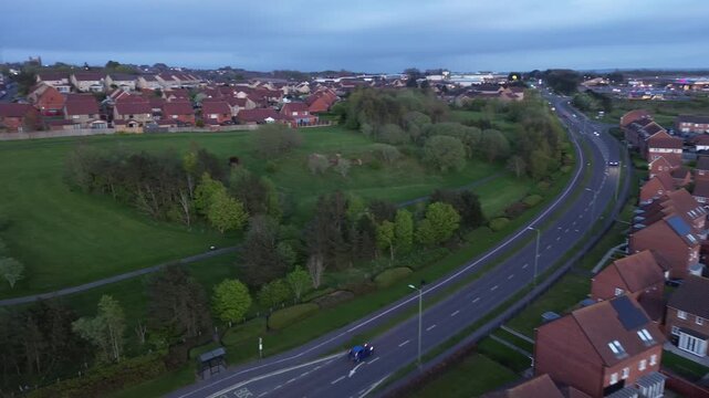 An ordinary British city, in the evening, viewed from above, with a street and moving cars