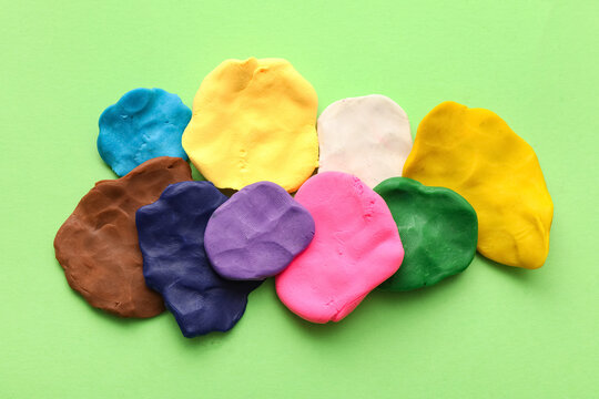 Many different colorful plasticine pieces on green background