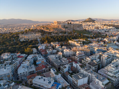 Aerial Image of the Acropolis, Parthenon, and Odeon of Herodes Atticus, overlooking the dense residential buildings of Athens at sunset.