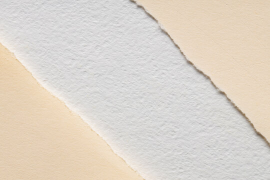 White handmade paper with torn deckled edge as a diagonal strip over a smooth cream background