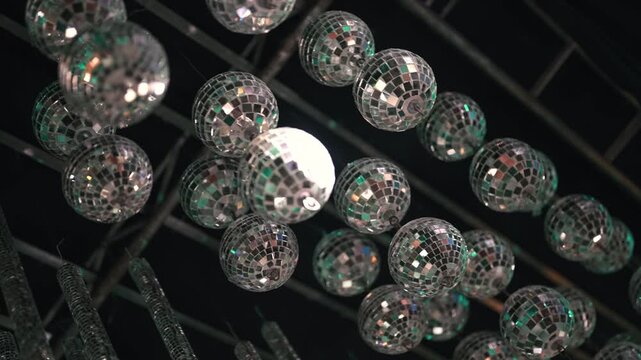 Multiple rows of disco balls create a mesmerizing pattern under dim lighting, ideal for event decor inspiration or nightlife promotions.