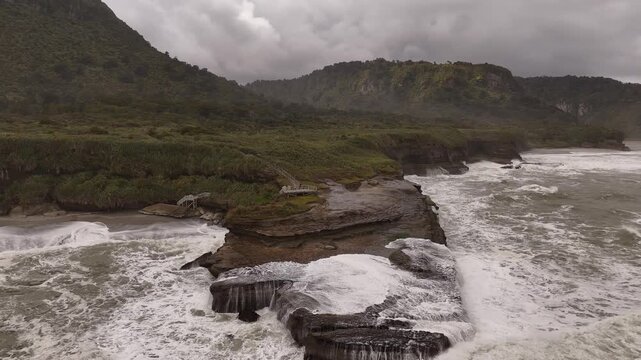 Raw power of Tasman Sea as large waves crash over rugged rock formations on Truman Track, New Zealand. Aerial drone view