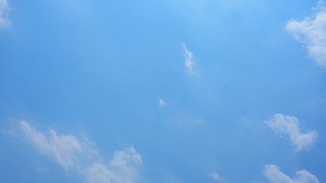 A blue sky timelapse video footage with soft white clouds drifting across a bright clear sky, capturing smooth atmospheric motion, natural daylight transitions, and a peaceful open-air ambiance. 4k.
