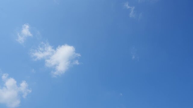 A blue sky timelapse video footage featuring scattered white clouds drifting across a vivid blue backdrop, capturing calm atmosphere, natural daylight shifts, and dynamic sky motion. 4k.
