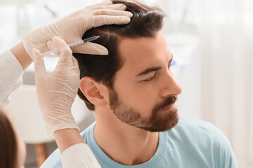 Fototapeta premium Doctor giving man injection for hair growth in clinic