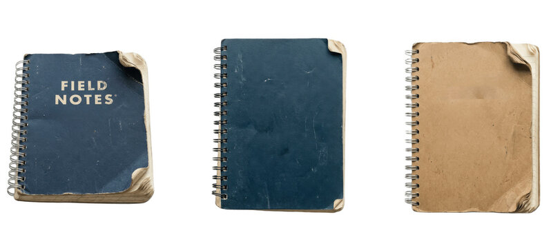 Worn spiral field notebooks with bent corners, blue and kraft covers, rugged vintage journals lined up for sketching, planning, and recording everyday thoughts

