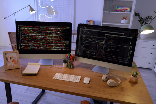 Programmer's desk with computer monitors and glowing lamps in office