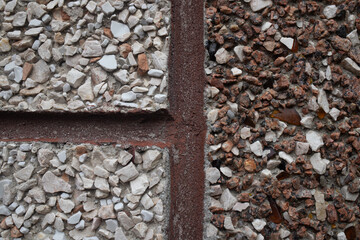 Close-up texture of a rustic exposed aggregate wall. A thick red brick mortar line separates sections of white/beige gravel from contrasting brown and reddish-brown pebbles and glass. © Tetiana
