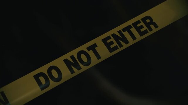 Yellow caution tape do not enter restricting access to dangerous zone at night indicating risk and perimeter control in dark outdoor environment