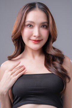 Beautiful Asian woman in denim shirt and black tube top smiling, young fashionable female posing in jeans on grey background