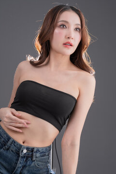 Beautiful Asian woman with healthy skin and long wavy hair smiling, glowing skin and beauty portrait of young female on grey background