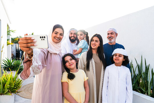 Arab multi-generational family wearing traditional emirati clothing taking selfie at home in Dubai