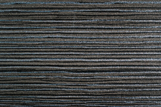 Dark grey HPL (High Pressure Laminate) texture with horizontal ribbed pattern. Close-up surface of decorative laminate material for furniture and interior design.