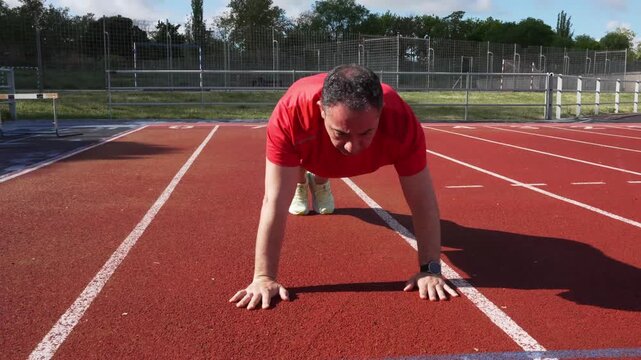 Man doing push ups exercise on a running track
