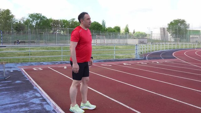 Male runner stretching quadriceps on athletics track