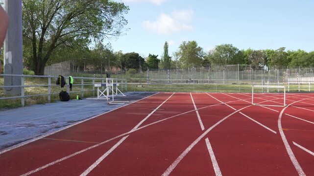 Male runner performing high knee warm-up on a stadium track