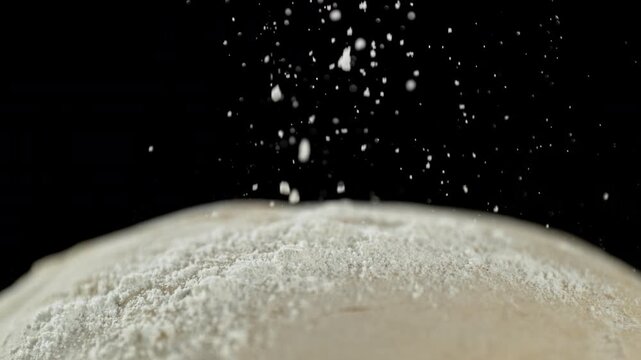 The dough on the kitchen table with falling flour . Filmed on a high-speed cinema camera at 1000 fps