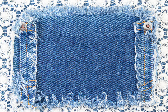 Denim patch on white lace background shows sewing details and texture in a crafting setting