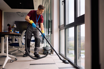 Professional cleaner vacuuming floors in modern office building.