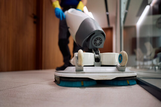 Close up of facility maintenance worker using professional floor cleaning machine.