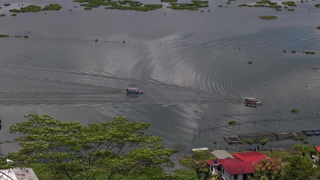 An aerial view of fishing boats and tourist boats crossing Rawa Pening Lake, a lake in Semarang Regency, Central Java, located in the basin of Mount Merbabu, Telomoyo, and Ungaran.