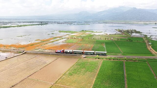 An aerial view of the Ambarawa Museum's vintage train journey across Lake Rawa Pening. A nostalgic journey using a diesel locomotive and classic wooden carriages.