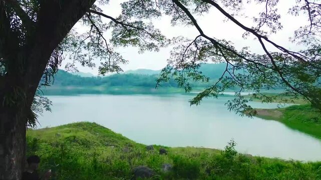 The calming natural scenery features clear water lakes, green hills, and shady trees, perfect for themes of tourism, relaxation, and natural beauty.