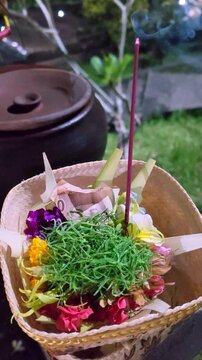 Traditional Balinese Canang Sari Offering with Burning Incense and Indonesian Rupiah