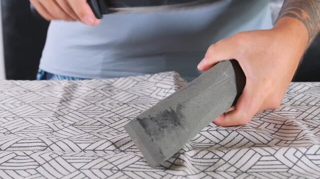 Close-up of person sharpening kitchen knife on whetstone, precise blade honing process, maintaining sharp edge at home, culinary tool care and traditional sharpening technique