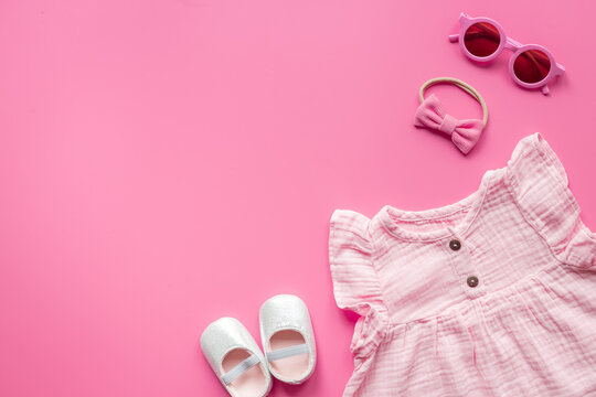 Baby girl pink cotton muslin dress with shoes and accessories, top view. Kids stylish summer clothes