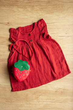 Red baby girl cotton muslin dress with strawberry-shaped handbag, top view