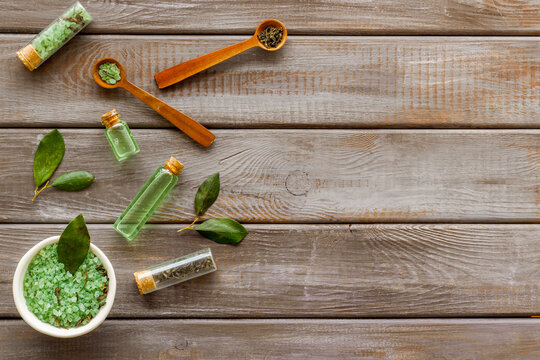 Organic cosmetics products - tea tree essential oil and sea salt near green leaves top view.