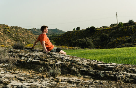Young man relaxing on rock in nature landscape