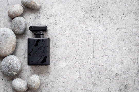Stylish black perfume bottle with water drops. Male fragrance concept
