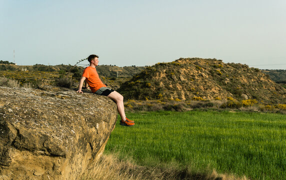 Young man contemplating nature while sitting on rock