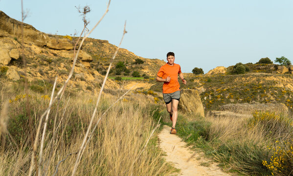 Young man trail running on mountain path
