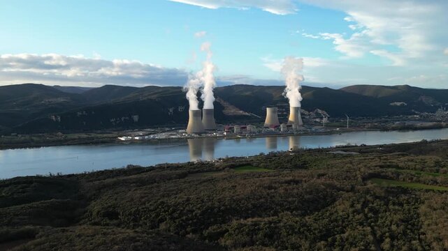 Cruas, France - 20 February 2026: Aerial drone view of the Cruas nuclear power plant in France, with cooling towers producing steam beside the Rh&ocirc;ne River during a dramatic sunny afternoon landscape.