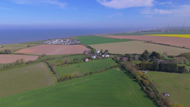 A drone orbit of a windmill and a field of green wheatgrass on the coast in North Norfolk in the UK