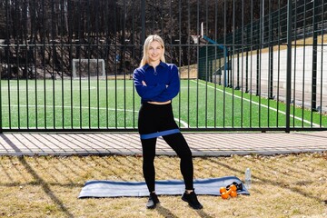 Obraz premium Confident sportswoman posing with resistance band on a sports field