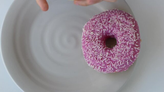 Child hands choosing strawberry and pistachio donut from assortment in top view, consumer choice concept for retail and food marketing visuals. Donut selection, decision behavior and product variety.